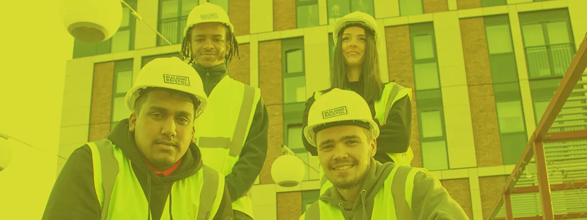 Apprenticeship students posing outside building with hi-vis vests and helmets on