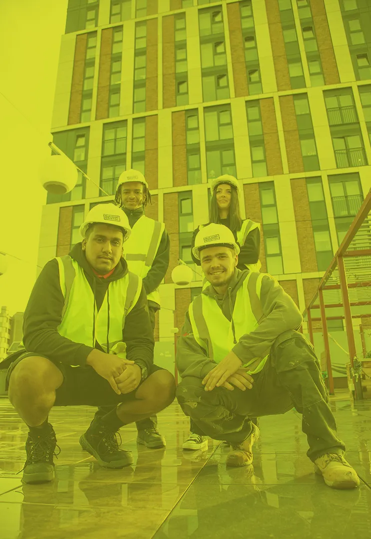Apprenticeship students posing outside building with hi-vis vests and helmets on